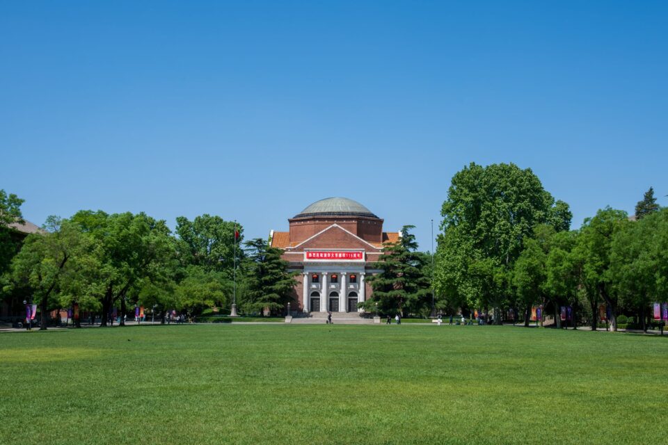 A brick university building surrounded by a green lawn and trees, evoking the campus character of College Station, TX