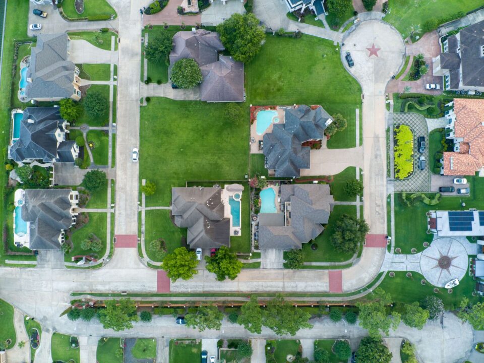 Aerial view of a Houston-area suburban neighborhood with pools and green lawns, typical of Katy, TX