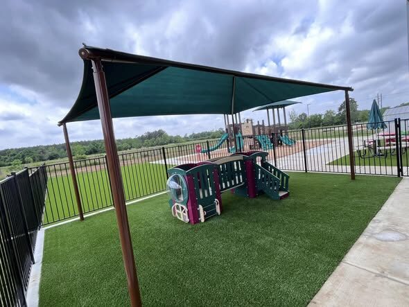 Artificial turf around a shaded play structure at a church daycare in Tomball, TX