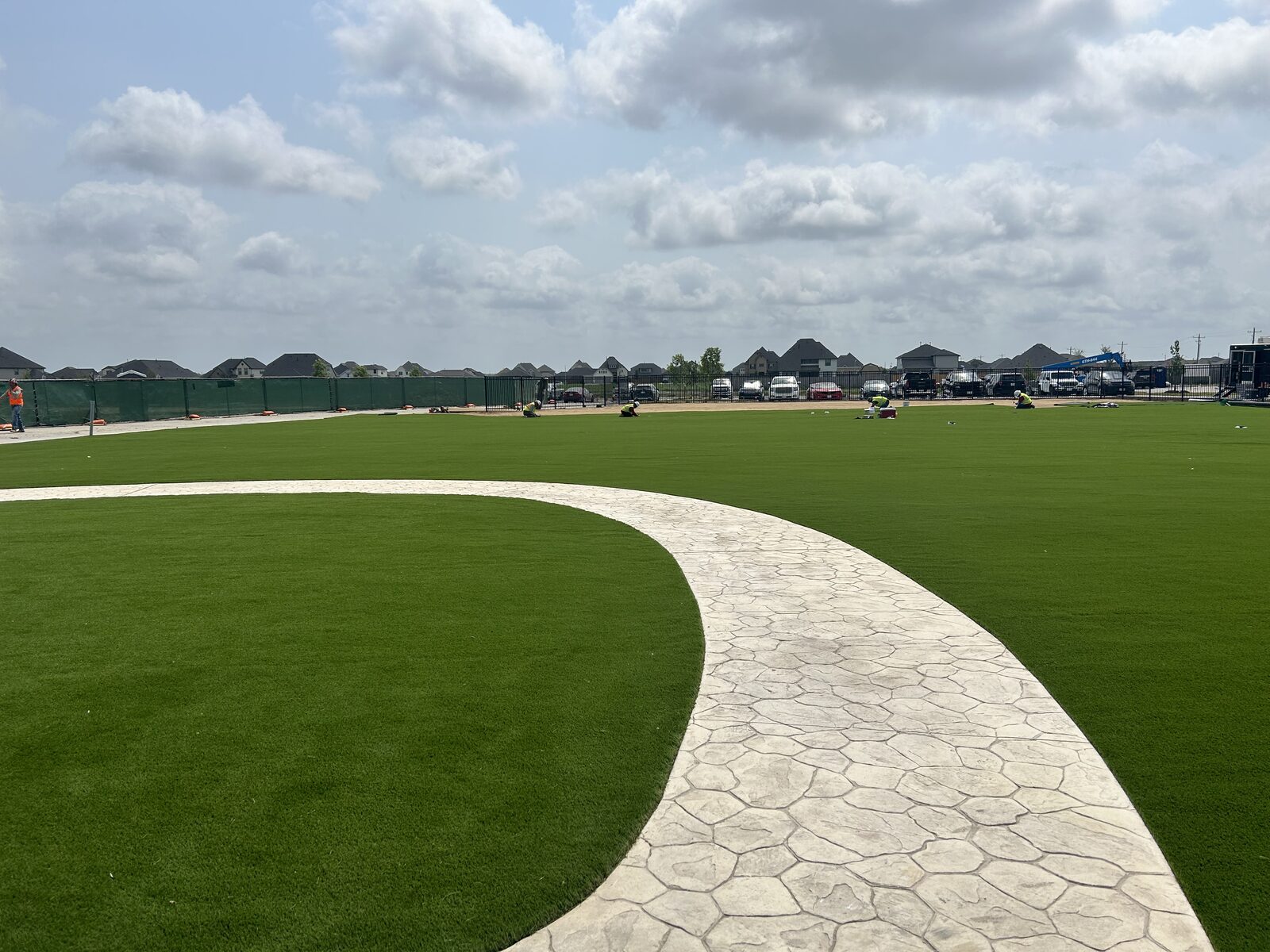 Commercial artificial turf event lawn with curved concrete walkway at Angel Lagoon in Dayton, TX