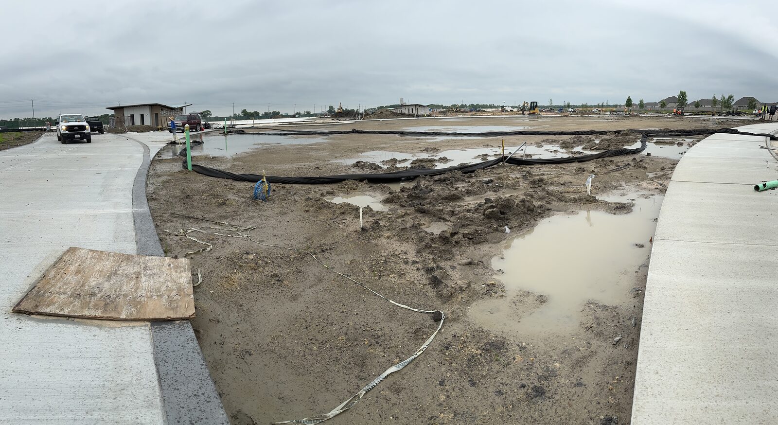 Raw clay commercial site holding standing water in Dayton, TX before artificial turf installation