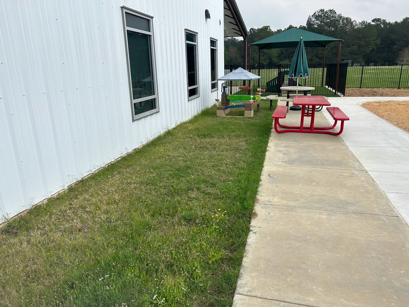 Worn natural grass and bare soil at Graceview Baptist Church childcare play area before artificial turf installation