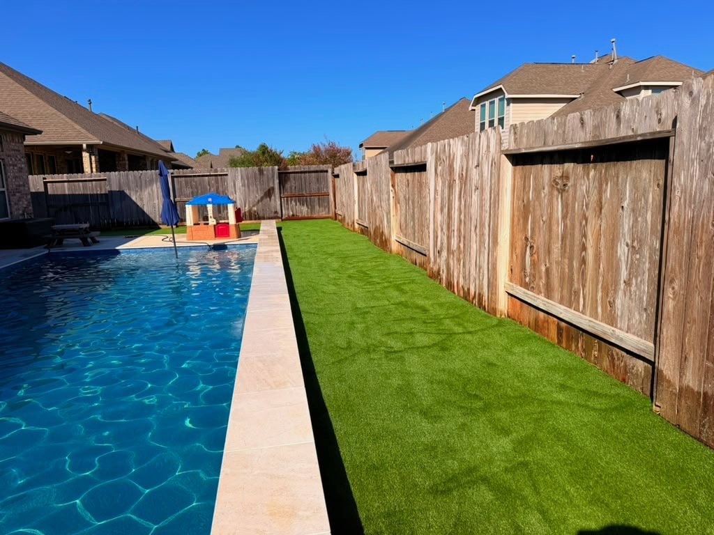 Artificial turf between a new pool and the fence in a Tomball, TX backyard