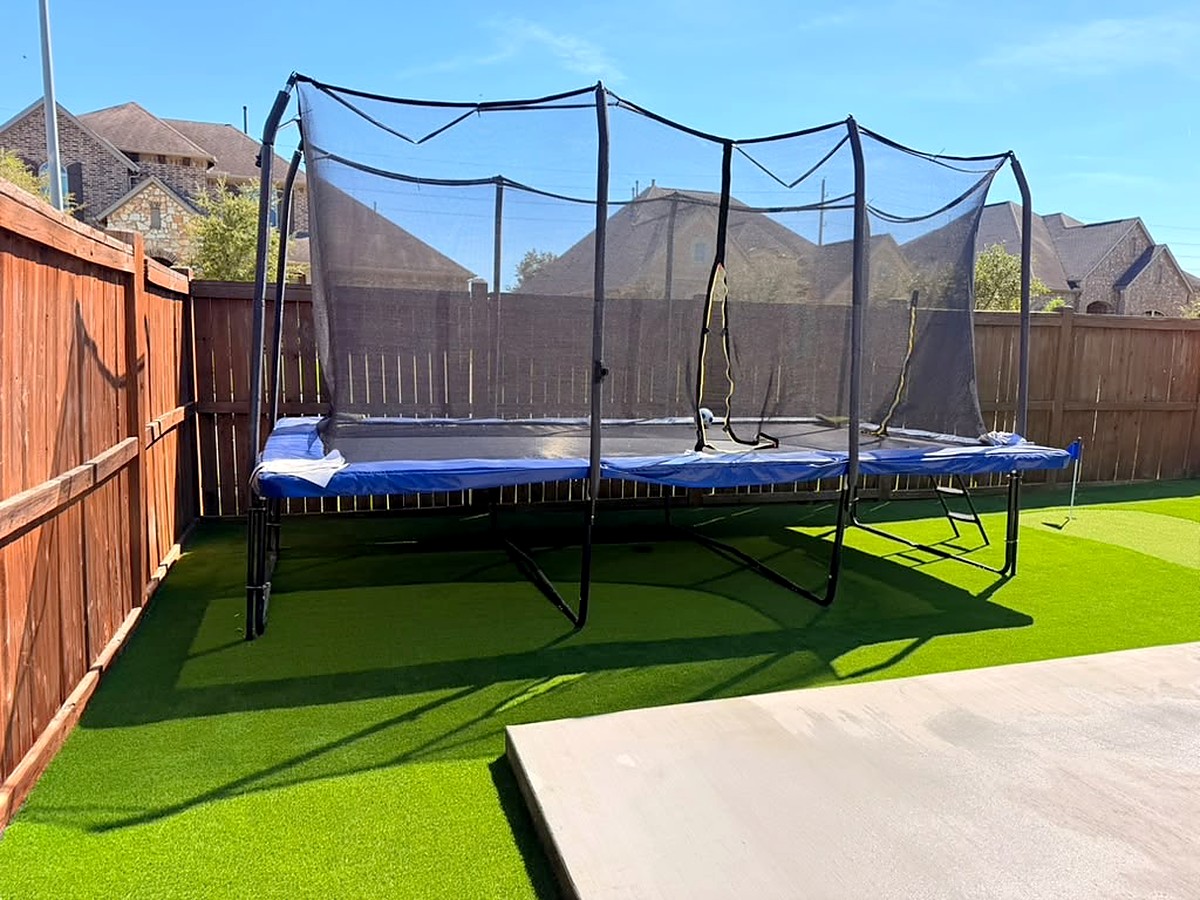 Artificial turf under a trampoline in a fenced backyard in Spring, TX