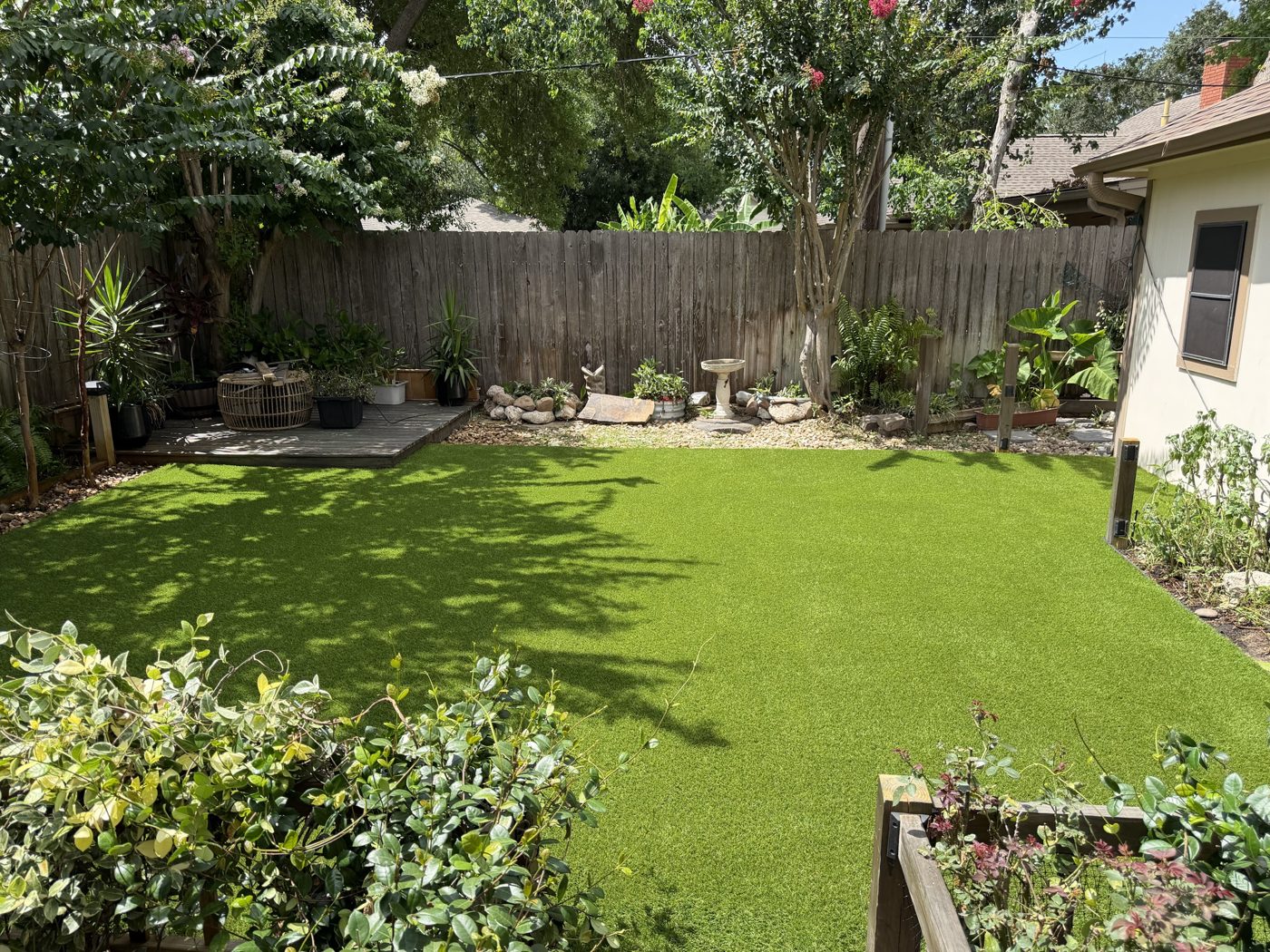 Pet turf dog yard with a wood deck and garden beds in Willis, TX