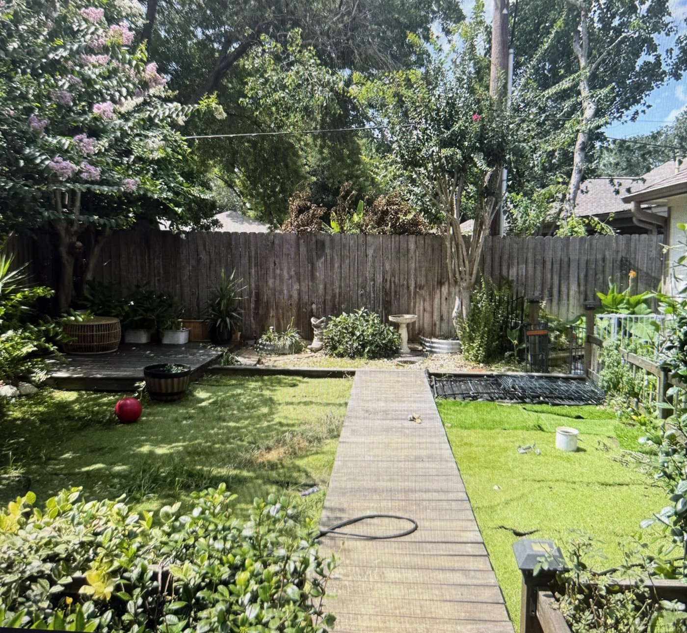Old worn turf and a wood walkway in a Willis, TX backyard before new pet turf