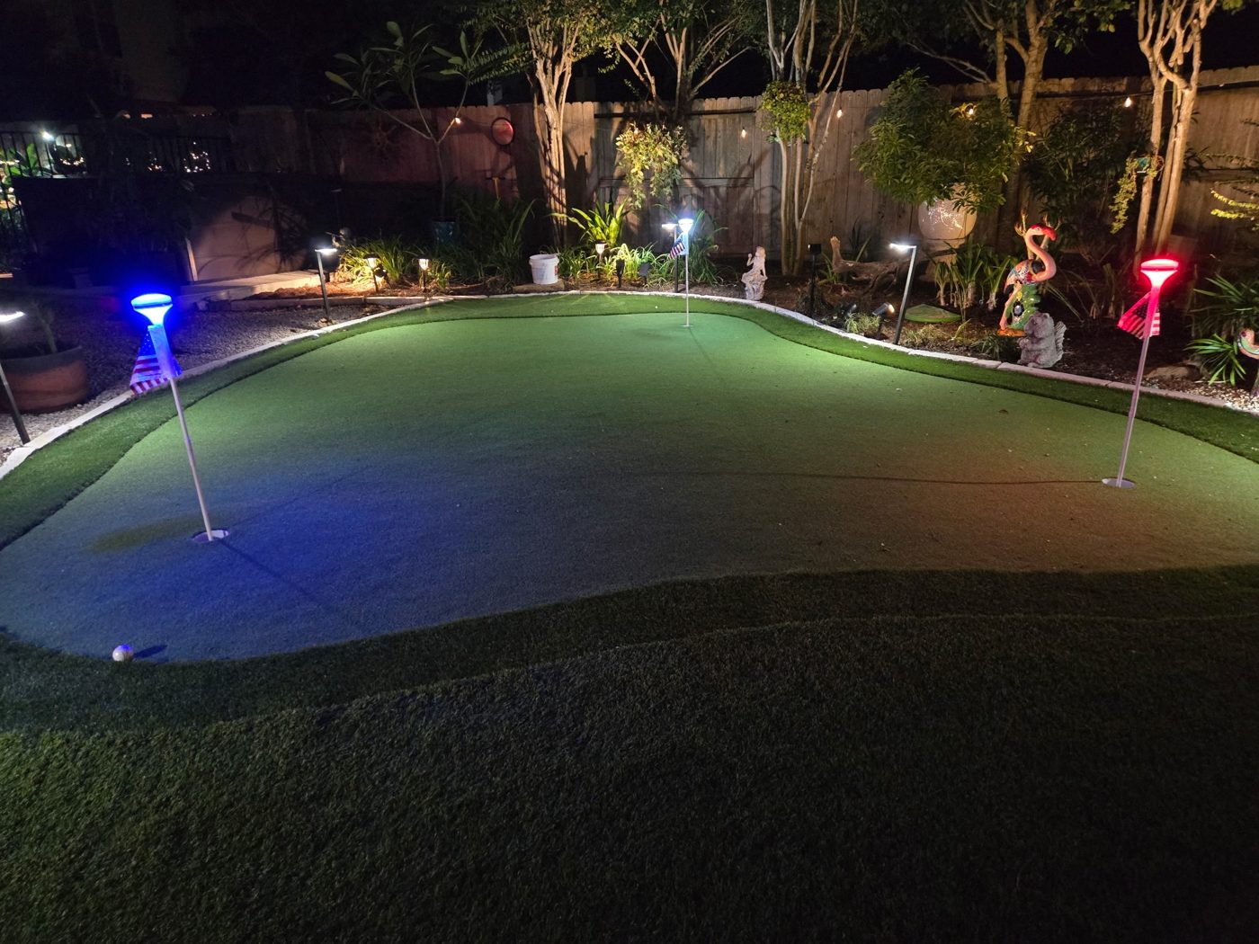 Backyard putting green with lighted flags at night in Fulshear, TX