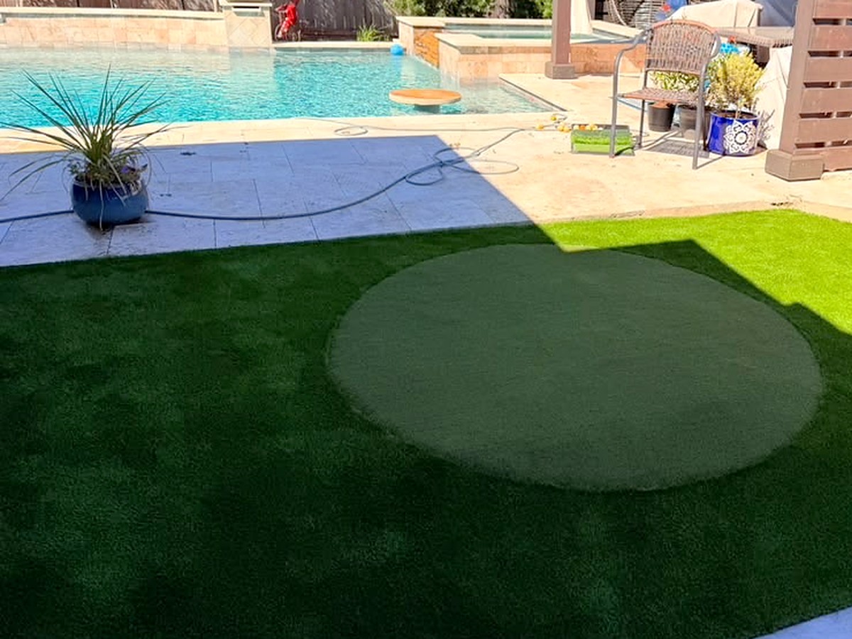 Round artificial turf putting green next to a pool in Spring, TX