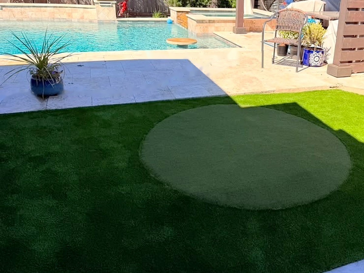Round artificial turf putting green next to a pool in a Spring, TX backyard